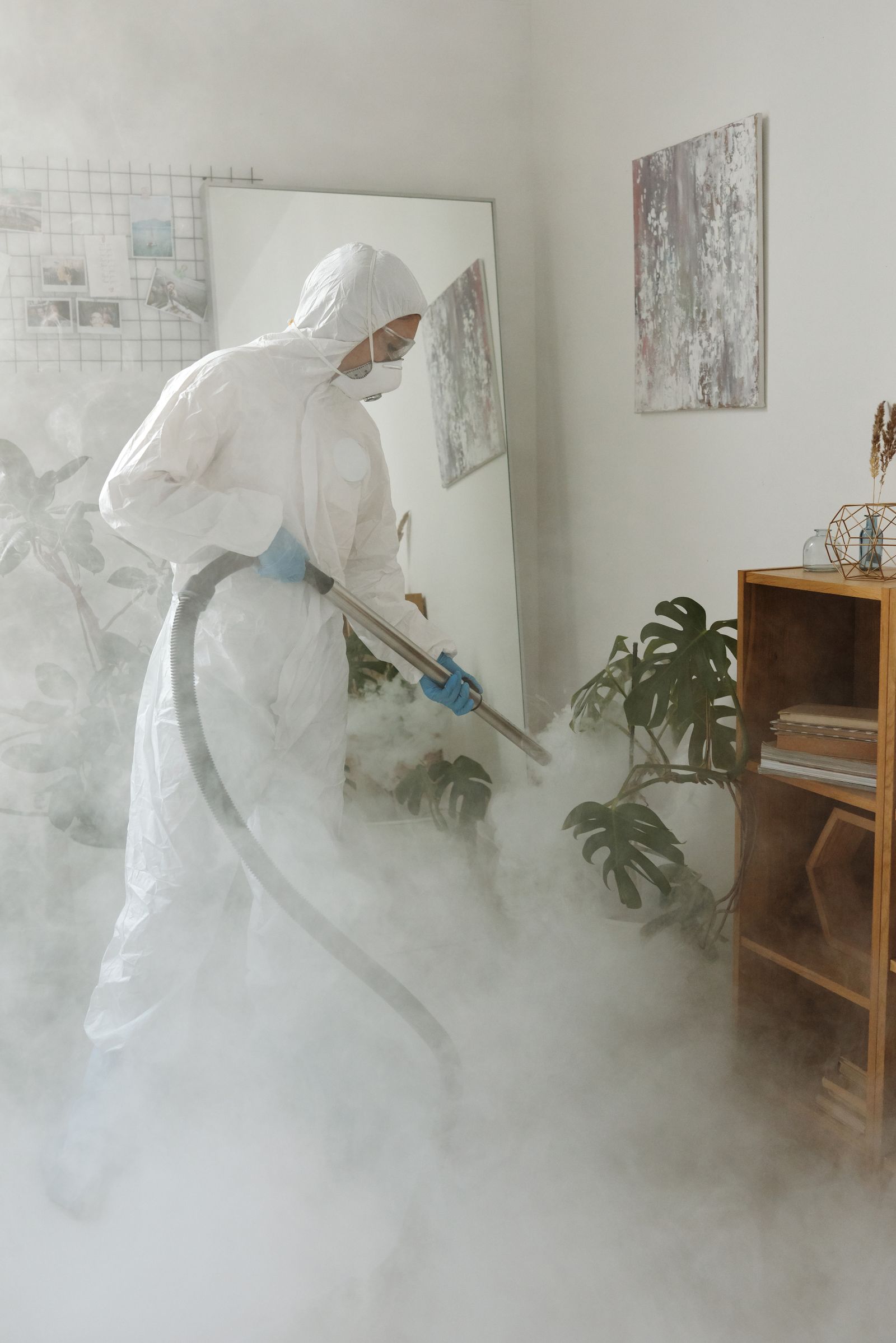 Técnico con traje de protección sanitizando un espacio
